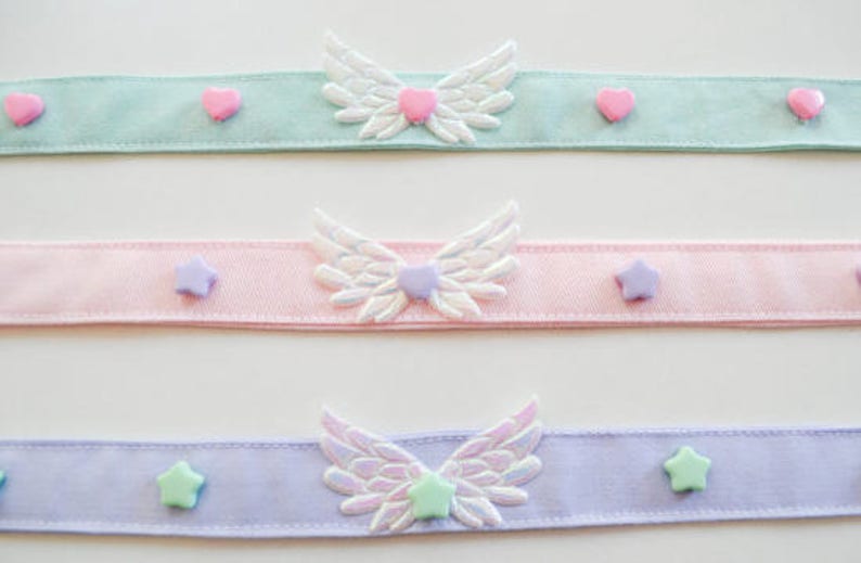 May include: Three pastel colored ribbon chokers with white wings and pastel colored heart and star embellishments.