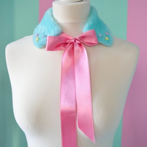 May include: A light blue faux fur collar with pastel colored star embellishments and a pink satin bow tie.