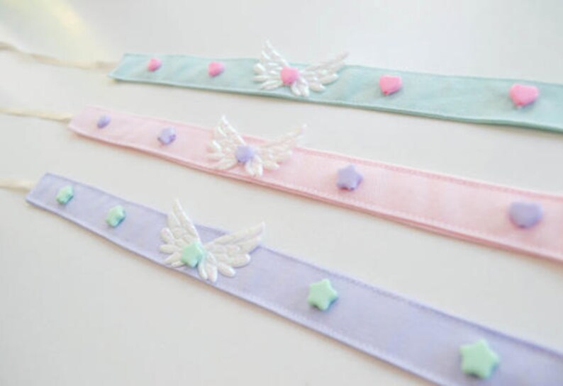 May include: Three pastel ribbon headbands with white wings and pastel colored star and heart embellishments.