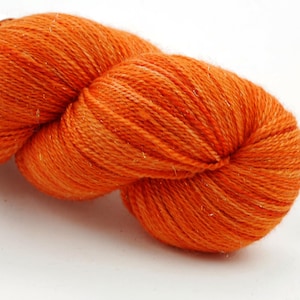 Puede incluir: Un ovillo de hilo naranja con un brillo sutil.