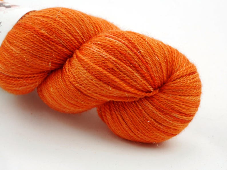 Puede incluir: Un ovillo de hilo naranja con un brillo sutil.