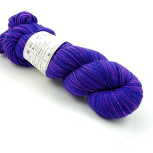 May include: A skein of purple and pink yarn with a white label that says "Tros & Co."