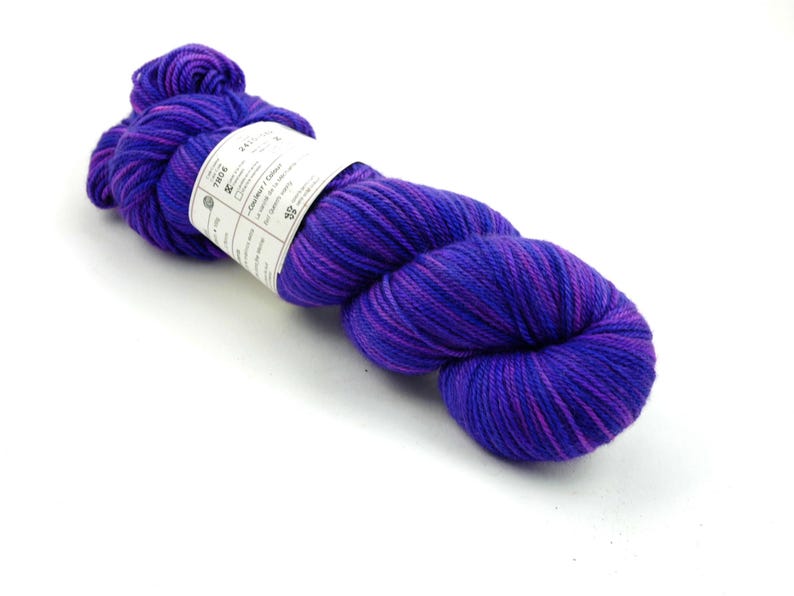 May include: A skein of purple and pink yarn with a white label that says "Tros & Co."