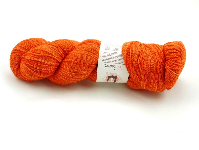 Puede incluir: Un ovillo de lana naranja con una etiqueta blanca que dice "Wool and the Gang".