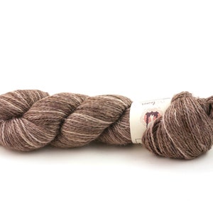 Op de afbeelding: Een bol bruin en wit garen met een label waarop "The Loopy Ewe" staat.