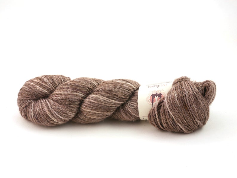 Op de afbeelding: Een bol bruin en wit garen met een label waarop "The Loopy Ewe" staat.