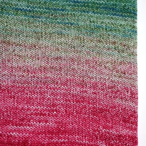 May include: A close-up of a knitted fabric with a gradient of colors, starting with a dark green at the top and transitioning to a bright pink at the bottom.