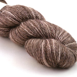 Op de afbeelding: Een bol bruin en wit garen met een subtiele roze tint. Het garen is gemaakt van wol en alpaca vezels.