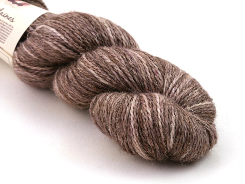 Op de afbeelding: Een bol bruin en wit garen met een subtiele roze tint. Het garen is gemaakt van wol en alpaca vezels.