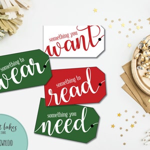 Puede incluir: Cuatro etiquetas de regalo imprimibles en un esquema de color rojo y verde. Las etiquetas tienen forma de rectángulo redondeado con un agujero perforado en la esquina superior. El texto en las etiquetas dice "algo para vestir", "algo que quieres", "algo para leer" y "algo que necesitas".