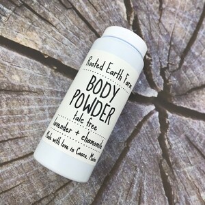 May include: White plastic container of Rooted Earth Farm body powder, labeled "talc free lavender + chamomile" and "Made with love in Casco, Maine".