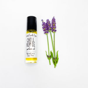 Puede incluir: Un peque&ntilde;o frasco de vidrio de aceite de perfume con una etiqueta blanca que dice "CHILL HIPPIE perfume oil" y "Made with love in Casco, Maine". El frasco est&aacute; sobre una superficie blanca junto a tres ramitas de lavanda.