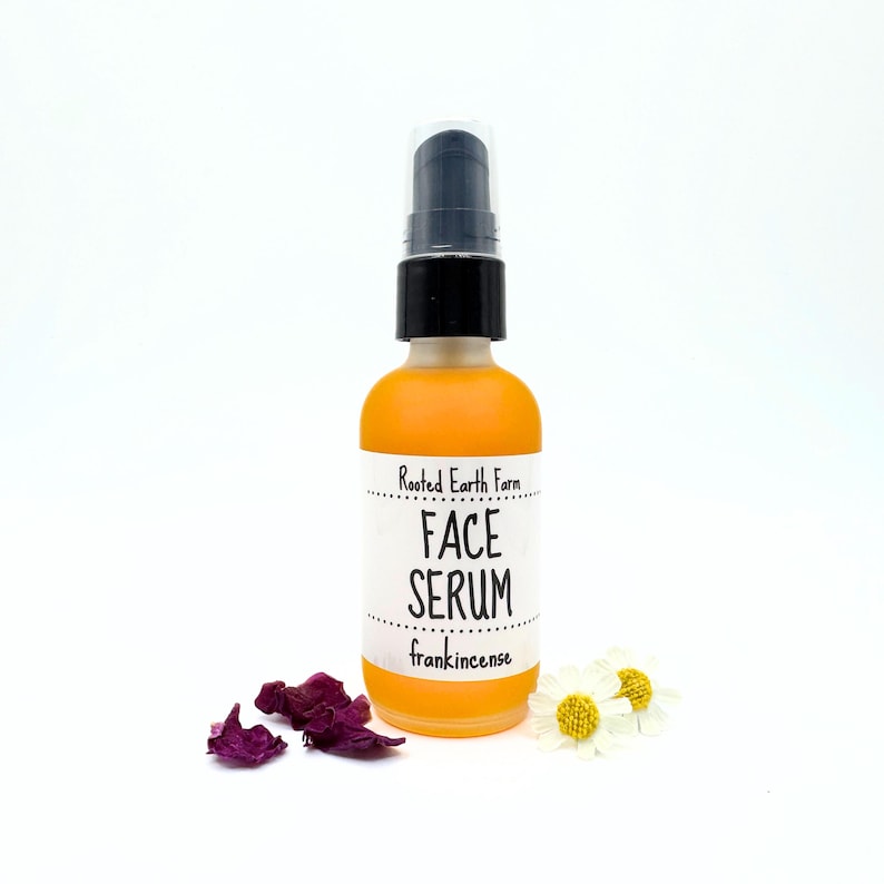 May include: A clear glass bottle with a black pump top filled with a yellow liquid. The bottle has a white label that reads "Rooted Earth Farm Face Serum frankincense".