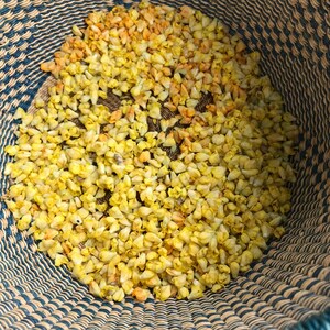 Puede incluir: Una cesta tejida llena de capullos de flores amarillas secas.