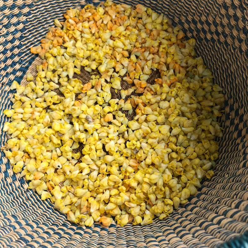 Puede incluir: Una cesta tejida llena de capullos de flores amarillas secas.