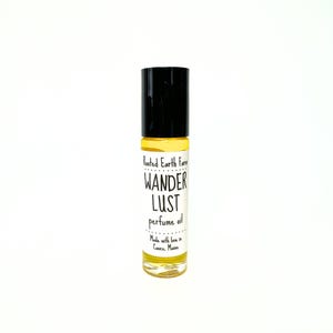 May include: A small glass bottle of perfume oil with a black roll-on top. The label reads "Rooted Earth Farm Wander Lust perfume oil Made with love in Casco, Maine."