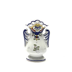 May include: A white ceramic vase with a detailed floral design. The vase features blue, yellow, and red accents, with two handles and a scalloped rim. The vase is approximately 8 inches tall.
