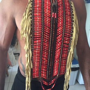 May include: A red and black beaded necklace with fringe. The necklace is made of leather and has a long, beaded pendant.
