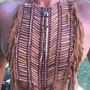 Peut inclure: Un collier en cuir marron et en perles de bois avec des franges. Le collier est composé de petites perles de bois et de lanières de cuir. Les franges sont en cuir et pendent du bas du collier.