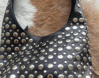May include: Black leather shoulder bag with silver-colored circular studs. The bag has a curved shape and a single shoulder strap. The studs are evenly spaced across the surface of the bag.
