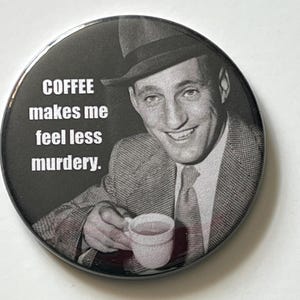 May include: A round, black and white button featuring a vintage image of a man in a suit and fedora holding a coffee cup. The text on the button reads, "COFFEE makes me feel less murdery."