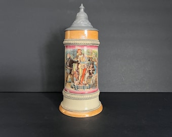 May include: A tall, decorative beer stein with a hinged metal lid. The ceramic body features a colorful scene of figures in period clothing. The stein has orange, pink, and cream-colored bands with silver-colored trim.