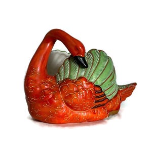 May include: A ceramic swan-shaped decorative container. The swan features a vibrant orange body with gold accents, a green and white wing, and a black beak. The container is designed to hold small items.