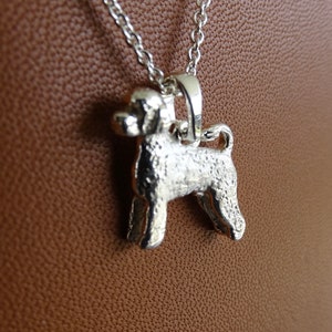 May include: Silver pendant necklace featuring a detailed, textured, 3D design of a Portuguese Water Dog.
