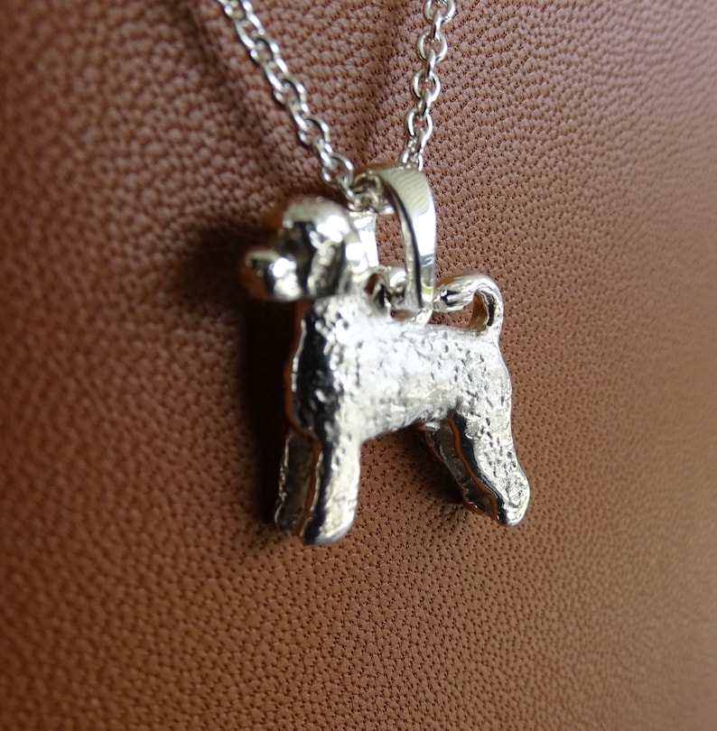 May include: Silver pendant necklace featuring a detailed, textured, 3D design of a Portuguese Water Dog.