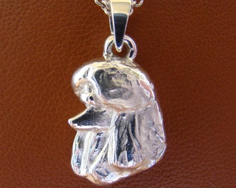 Puede incluir: Colgante de plata en forma de caniche. El colgante es detallado y tiene una superficie texturizada.