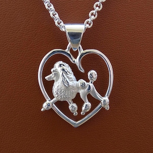 Colgante pequeño con diseño de caniche en movimiento y marco de corazón en plata de ley