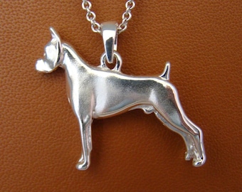 Puede incluir: Un collar con un colgante de plata que presenta una silueta de perro boxer tridimensional detallada.