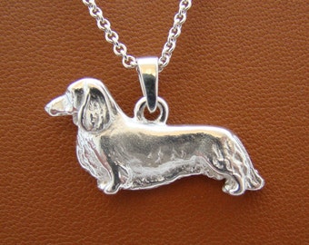 May include: Silver dachshund pendant necklace. The pendant is a detailed, realistic depiction of a dachshund dog.