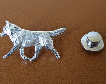 Op de afbeelding: Zilverkleurige broche met een gedetailleerd ontwerp van een lopende husky-hond. De broche heeft een veilige sluiting aan de achterkant.