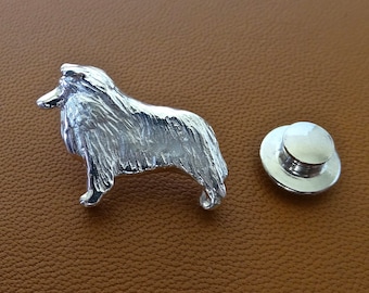 Puede incluir: Pin de metal plateado de un perro Collie de perfil, mirando hacia la derecha. El pin tiene una superficie texturizada para parecer pelaje. El pin viene con un cierre de metal plateado separado.