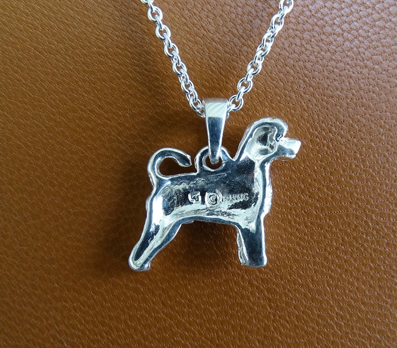 May include: Silver pendant necklace featuring a detailed silhouette of a dog. The pendant has a hallmark on the back.