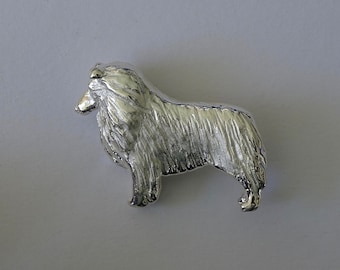 Puede incluir: Una figurita de un perro Collie esculpida en plata.