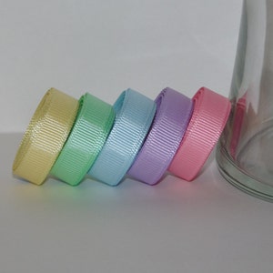 May include: Five spools of pastel colored ribbon, in shades of yellow, green, blue, lavender, and pink.