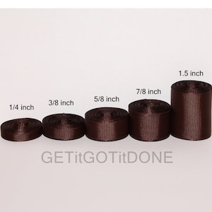 May include: Five rolls of brown grosgrain ribbon in varying widths: 1/4 inch, 3/8 inch, 5/8 inch, 7/8 inch, and 1.5 inches. The ribbon is neatly coiled, showcasing its texture and color. The text "GETitGO TitDONE" is at the bottom.
