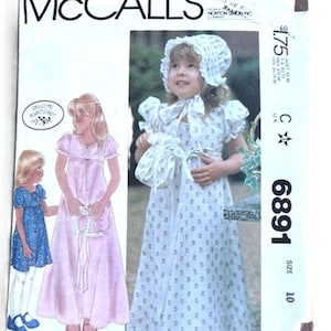 May include: Vintage McCall's sewing pattern featuring a girl's dress. The pattern envelope shows a young girl wearing a white dress with a floral print and matching bonnet. The text "McCall's" is prominently displayed at the top.