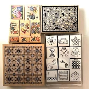 May include: A collection of wooden stamps featuring various designs. The stamps include images of spools of thread, stars, buttons, and geometric patterns. Some stamps are in a clear plastic case, while others are mounted on wooden blocks.
