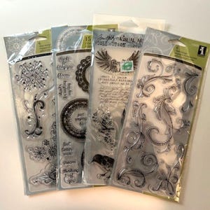 May include: A collection of clear stamps in plastic packaging. The stamps feature various designs, including snowflakes, floral patterns, and decorative elements. Some packages have text, including the words "Visual Art Collection".