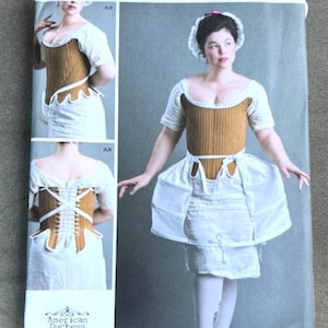 May include: Simplicity sewing pattern 8579 R5 featuring an American Duchess design. The pattern includes images of a historical costume with a brown corset and white skirt. The pattern size is US 14-22.