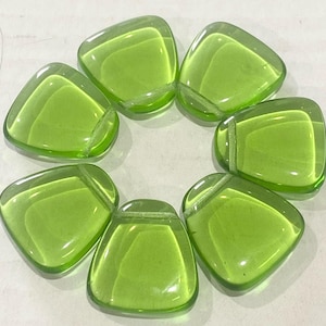 May include: Seven translucent, lime green glass tiles arranged in a circular pattern. Each tile has a rounded triangular shape with a slightly raised, rectangular top. The tiles are smooth and glossy, reflecting light.