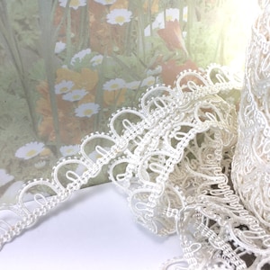 May include: White lace trim with a delicate scalloped edge. The trim features a repeating pattern of small loops and circles.