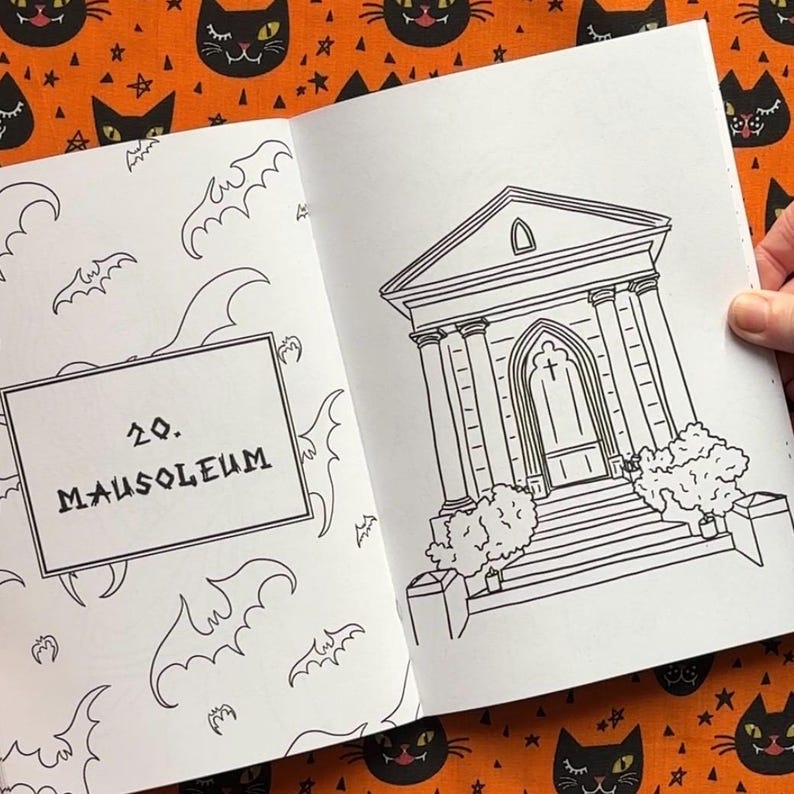 Pu&ograve; includere: Libro aperto con un'illustrazione in bianco e nero di un mausoleo. La pagina a sinistra presenta il testo "20. MAUSOLEUM" in un riquadro, circondato da disegni di pipistrelli. Lo sfondo &egrave; un tessuto arancione con facce di gatti neri.