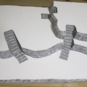 May include: A white foam model of a castle with gray stone details. The model has multiple levels and a series of steps leading up to the top.