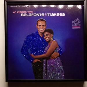Peut inclure: Une pochette d'album de disque vinyle vintage représentant un homme et une femme dans une étreinte serrée. L'album est intitulé "An Evening with Belafonte/Makeba" et présente un fond bleu avec le logo RCA Victor en haut à droite.
