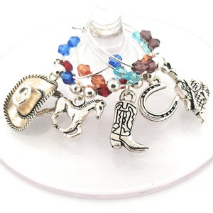 May include: Set of six silver-tone wine glass charms featuring a cowboy hat, horseshoe, boot, and horse. The charms are decorated with colorful beads.