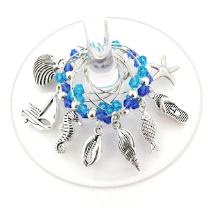 May include: Set of six blue and silver wine glass charms with nautical themed charms, including a seashell, a starfish, a sailboat, a seahorse, a fish, and a flip-flop.